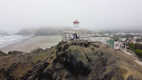 Toma-En-órbita-De-Personas-En-Pergula-Viendo-Vistas-Panorámicas-Al-Mar-En-Clima-Brumoso,-Perú