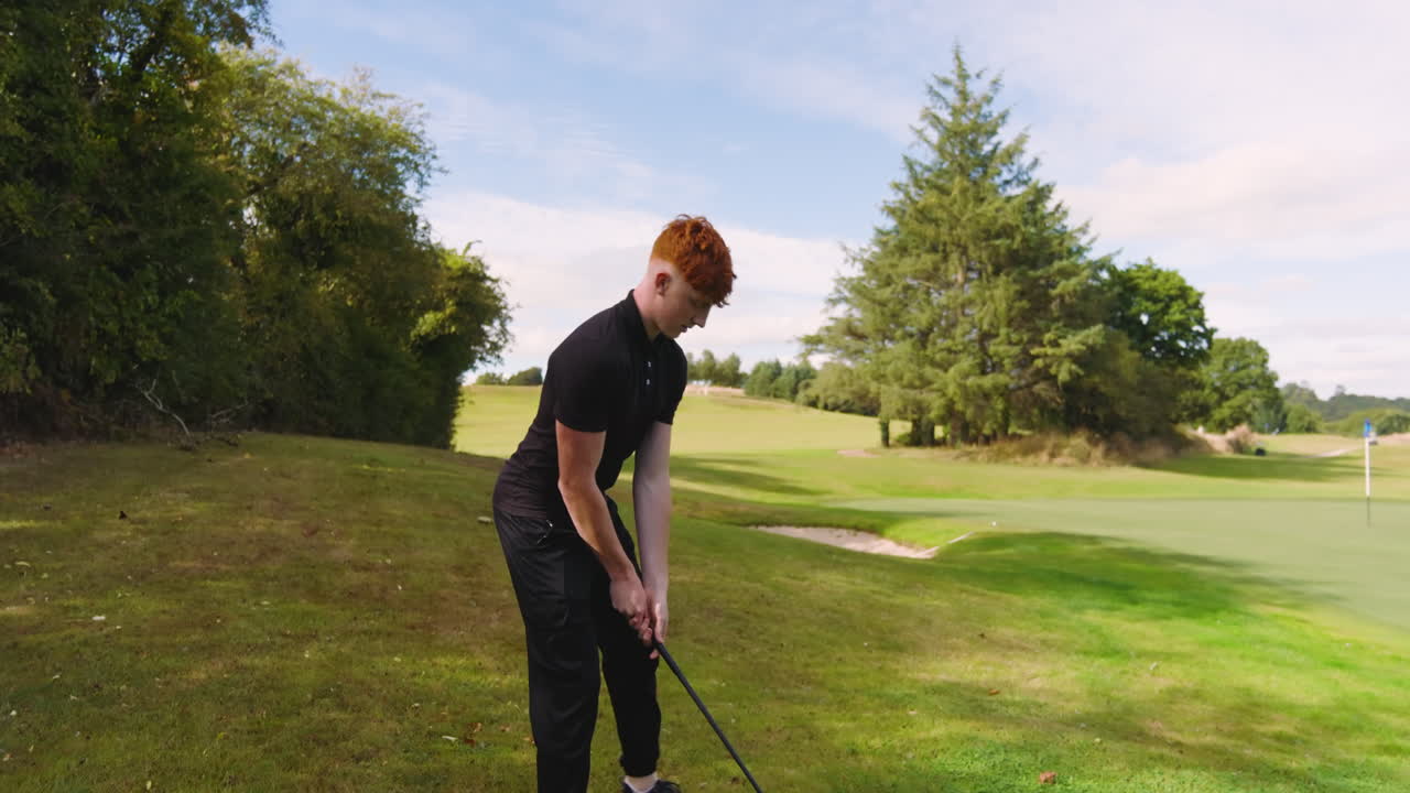 Male golf player playing golf, hitting the ball with club on a golf course on a sunny day