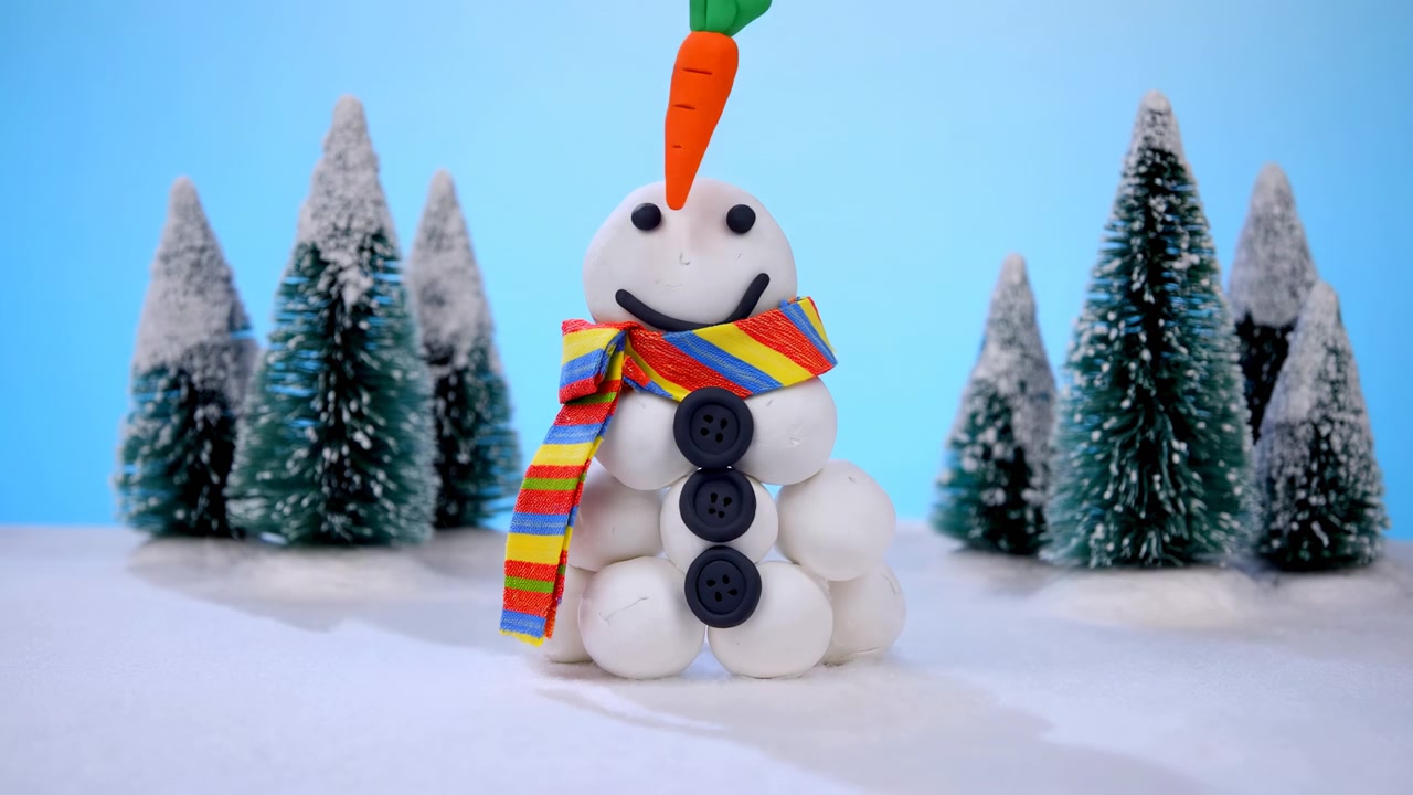Muñeco de nieve de arcilla ensamblado en un bosque nevado, bufanda a rayas de colores y nariz de zanahoria junto a una cara sonriente, miniatura