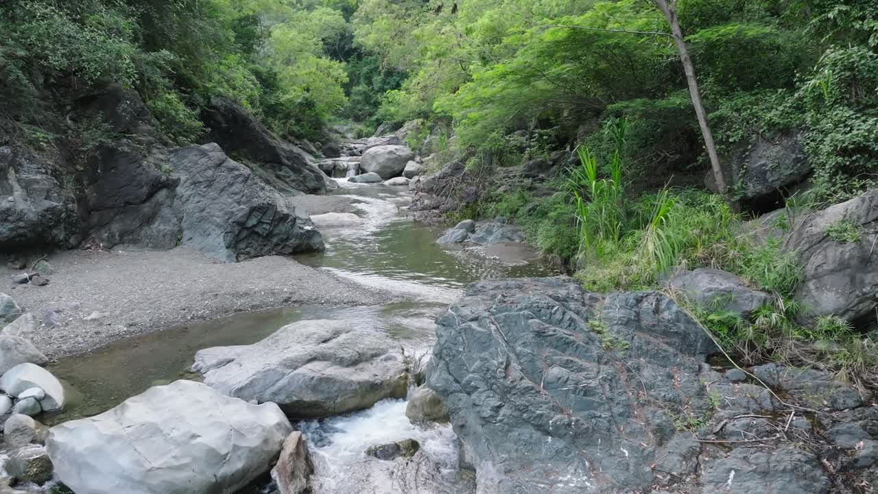 vuelo de avión no tripulado sobre un tranquilo arroyo rocoso en la zona tropical de la república dominicana durante el día