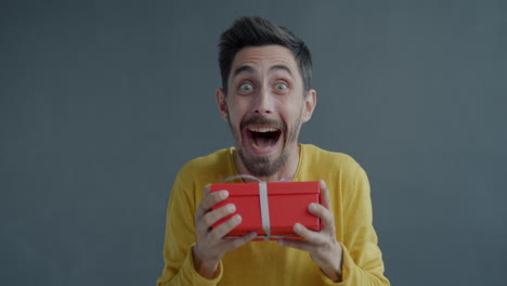 man excitedly holding a gift