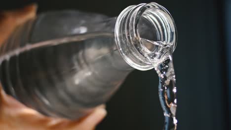 Mano-Masculina-Vertiendo-Un-Maravilloso-Chorro-De-Agua-De-Una-Botella-De-Vidrio,-Mantenerse-Saludable,-Hidratarse,-Cámara-Lenta,-Alta-Velocidad