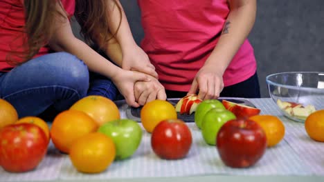 mother and child daughter preparing fruit. close up view of mother with her little daughter preparing food indoors