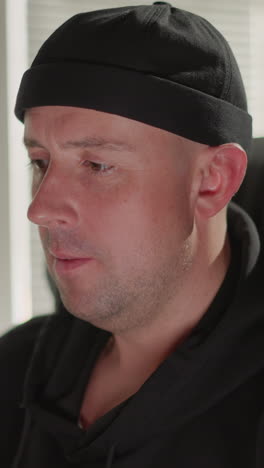 close-up of a man dressed in black, deeply focused on working at a computer in a recording studio. concentration as he is surrounded by sound equipment, with the camera zooming in