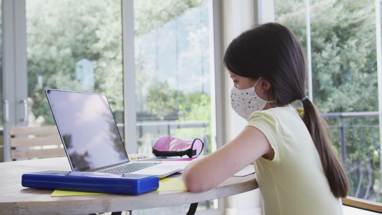 집에서 노트북을 사용하는 얼굴 마스크를 착용 한 소녀