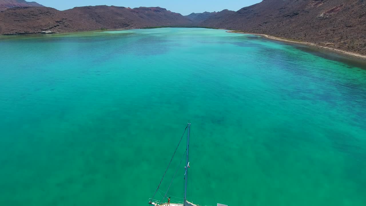 맑은 에메랄드 물 사막 코브에 정박한 범선을 탄 소녀의 공중 전망