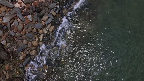 Drone-vertical-dolly-shot-of-granite-rocks,-beach-and-ocean-in-Thailand