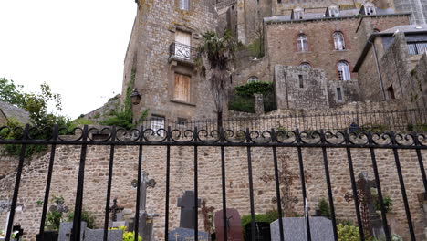 Tilt-up-shot-of-famous-cemetery-on-Le-Mont-Saint-Michel-Abbey-in-France-against-cloudy-sky