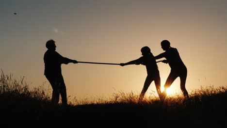 a strong older woman is competing with young people in tug-of-war active elderly people