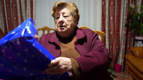 una anciana abre un regalo de cumpleaños en un hogar de ancianos.