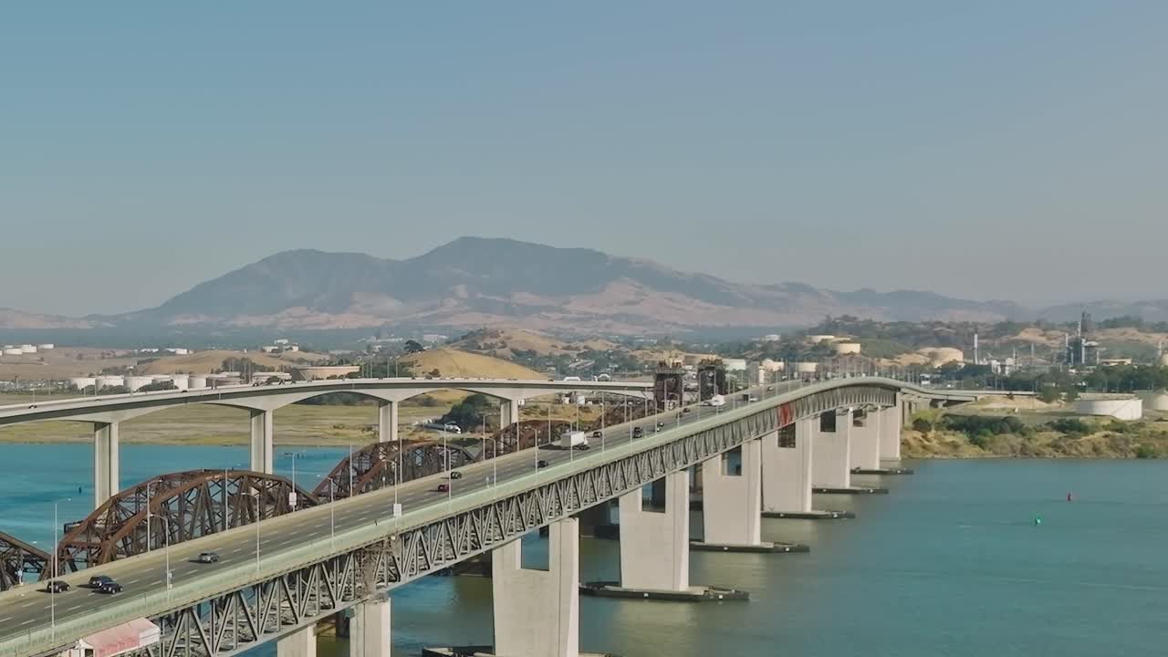 Cầu bắc qua mặt nước ở California gần núi với các phương tiện đang di chuyển.