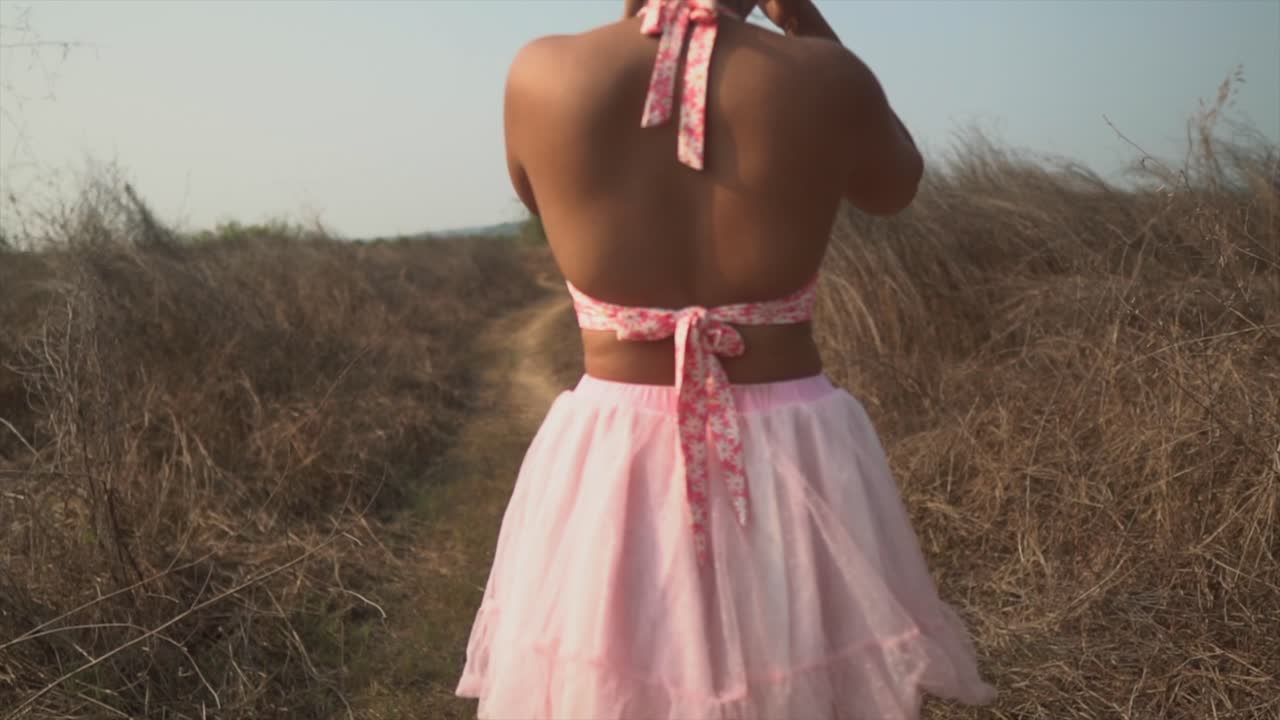 소녀는 패셔너블한 빨간 셔츠와 트렌디한 분홍색 치마를 입고 카메라를 지나서 촬영장으로 들어갑니다.