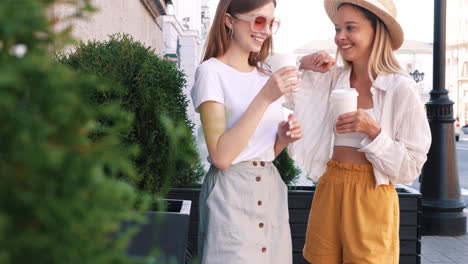 dos mujeres jóvenes disfrutando de café en una calle de la ciudad