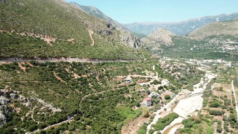 Albania,-aerial-view-from-a-drone-of-cars-driving-on-a-dangerous-road-along-a-steep-mountain-slope