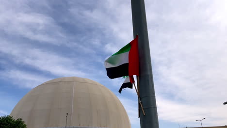 UAE-flag-proudly-fluttering-in-front-of-the-National-Theater-of-Abu-Dhabi,-Dubai