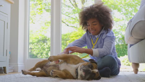 Boy-Pretending-To-Be-Veterinary-Surgeon-At-Home-Examining-Pet-French-Bulldog-With-Stethoscope