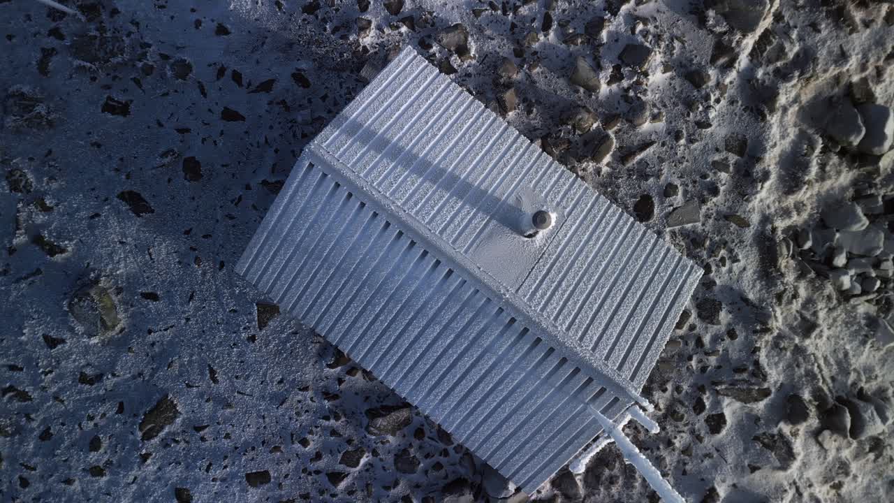 dron volando desde una cabina de emergencia en un movimiento rotacional que revela un paisaje helado y redondo