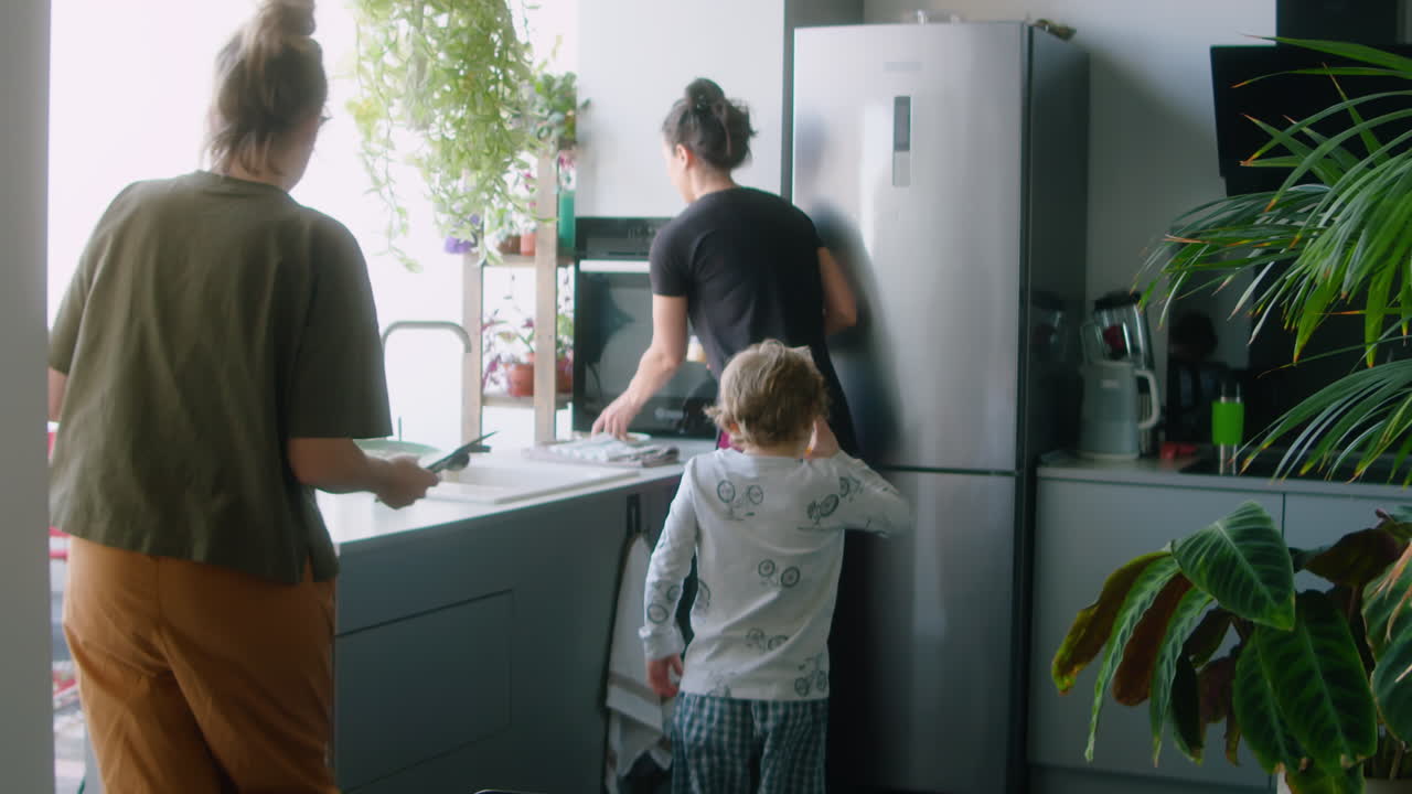 Lesbian Couple and Little Son Clearing Kitchen Table after Breakfast