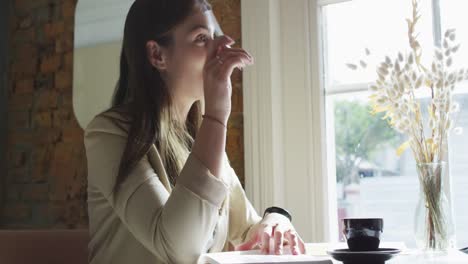 two caucasian businesswomen sitting at table with coffee, talking, having business meeting