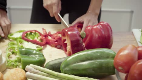 vista parcial de personas cortando verduras en la cocina