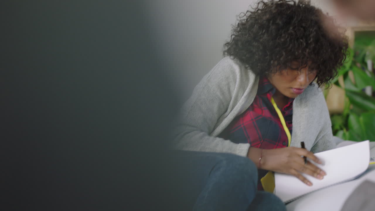 joven estudiante afroamericana estudiando trabajando en un proyecto escribiendo notas intercambiando ideas en una oficina multiétnica