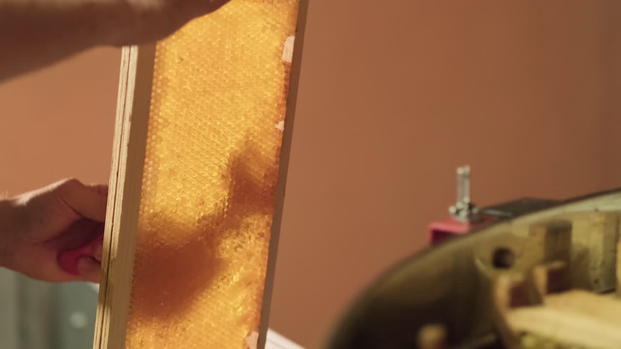 Beehive Wooden from Rack Waxen. beekeeper Hand Using A Knife spatula scraper to Clog Honeycombs With Honey In a Frame. Healthy natural apiculture super food