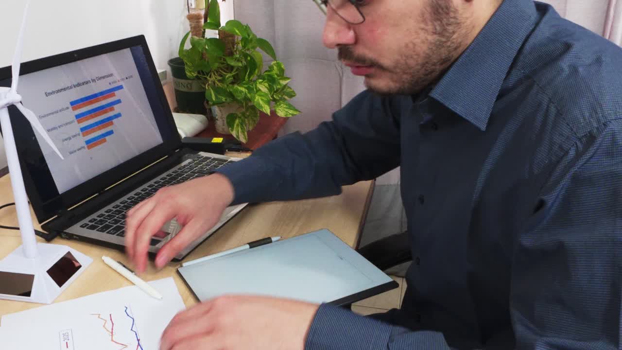 Engineer Multitasking with Laptop, Tablet, and Paper Reports