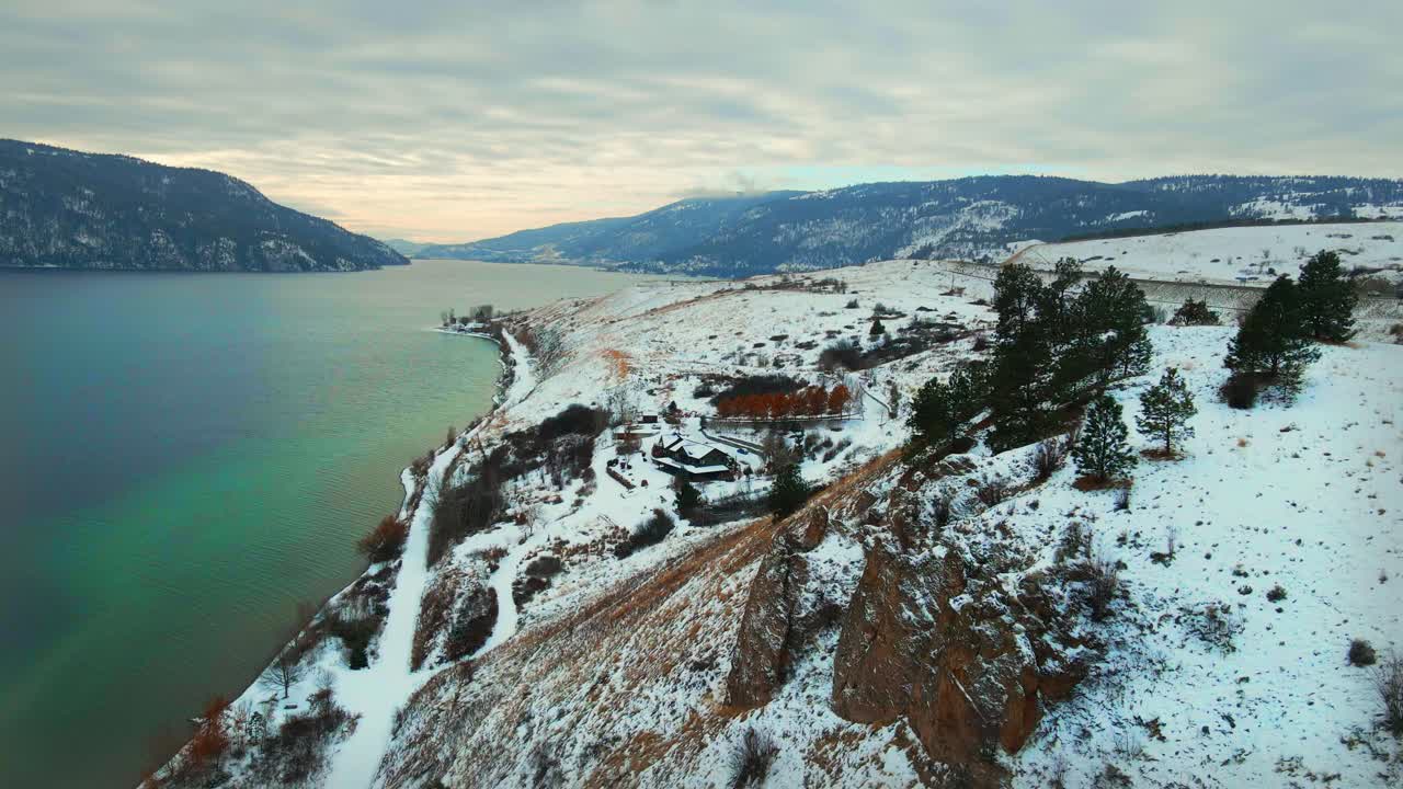 vista aérea del lago de madera turquesa en kelowna con acantilados rojos cubiertos de nieve a lo largo de la orilla