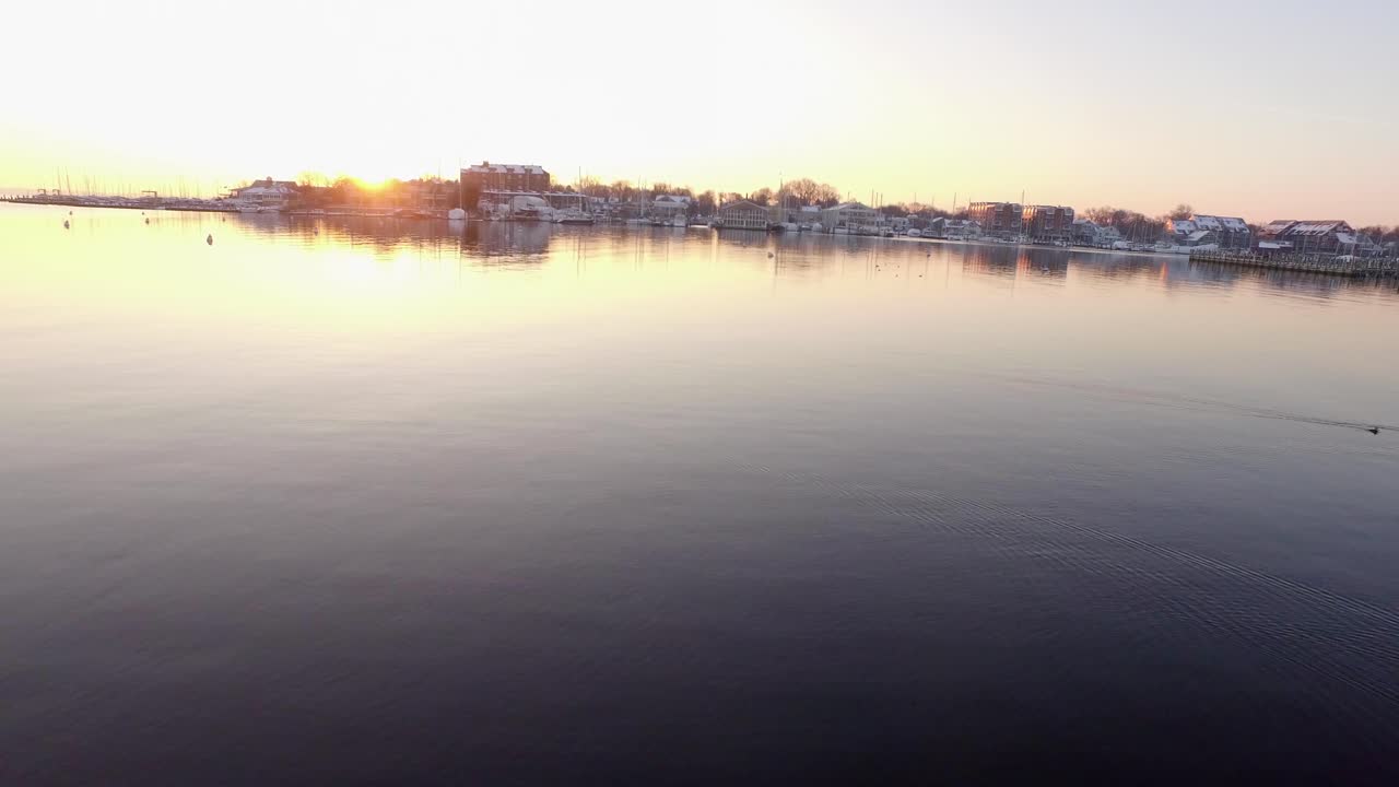 역사적인 아나폴리스 메릴랜드에서 황금빛 태양이 뜨는 동안 눈 덮힌 부두 매우 낮은 공중 발사가 말뚝 위로 그리고 강 위로 나갔습니다.