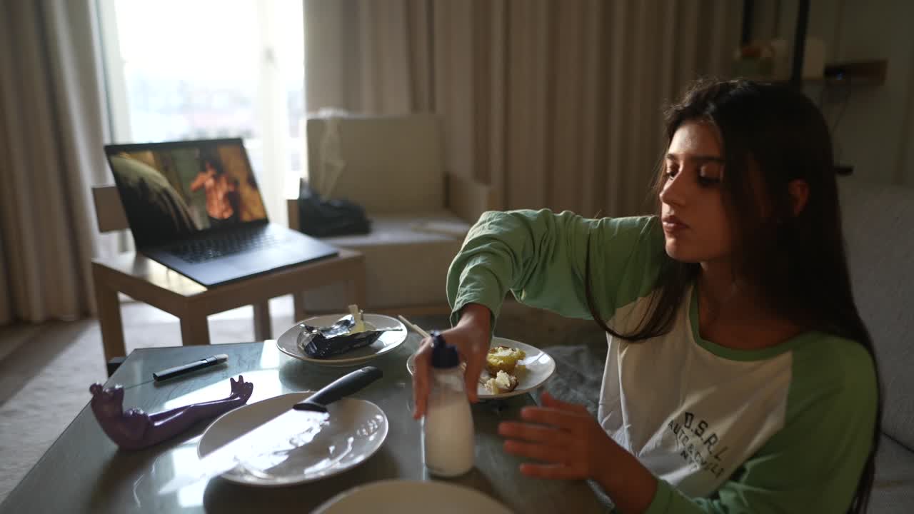 una mujer cenando mientras ve una película en casa.