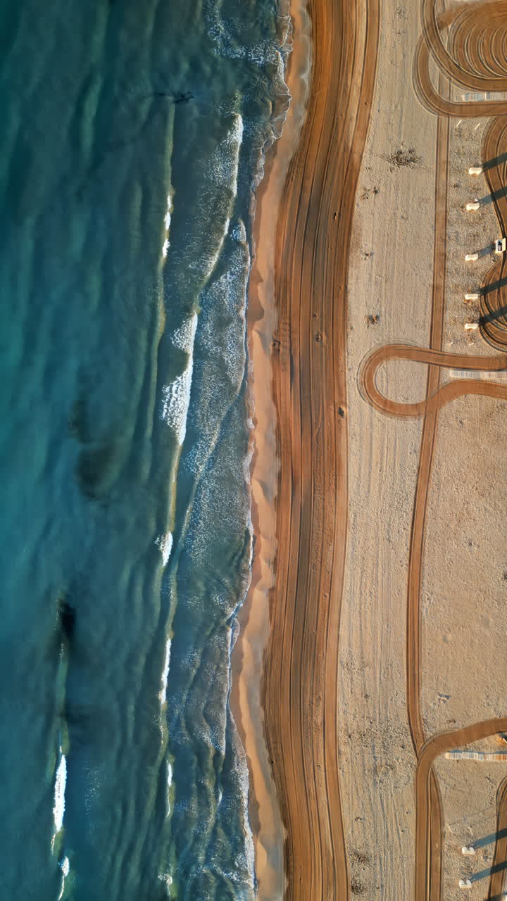 Vista aerea da drone delle onde che si infrangono sulla riva della spiaggia di Alicante, Spagna. Verticale