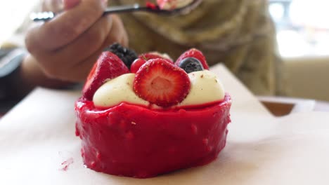 persona comiendo un pastel de terciopelo rojo con bayas