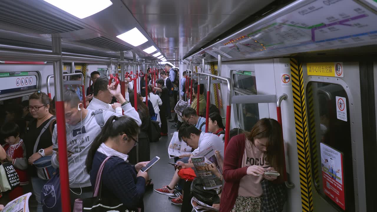 Commuters on a crowded Mass Transit Railway or MRT train on the Hong Kong underground transport network. Static handheld shot