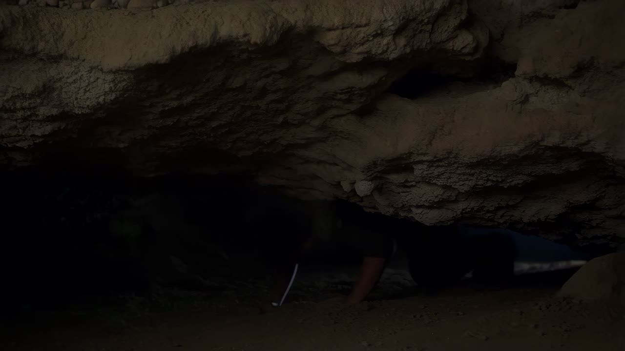 Person Under Falling Debris in a Dark Cave