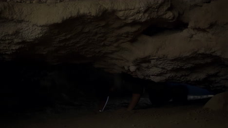 person under falling debris in a dark cave