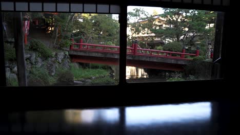 vista desde las ventanas de ryokan shoji del puente rojo sobre el estanque koi en el jardín zen japonés
