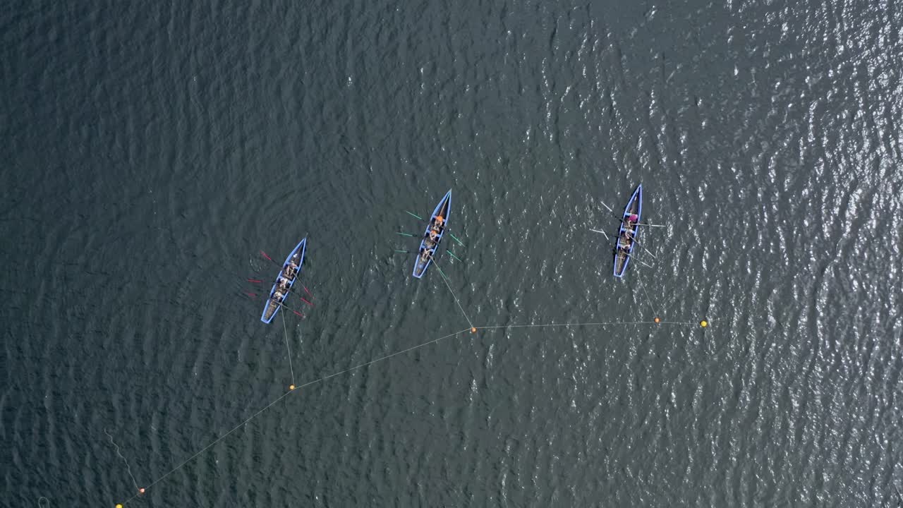 Top down rising bird's eye view above currach boats anchored to buoys at start line
