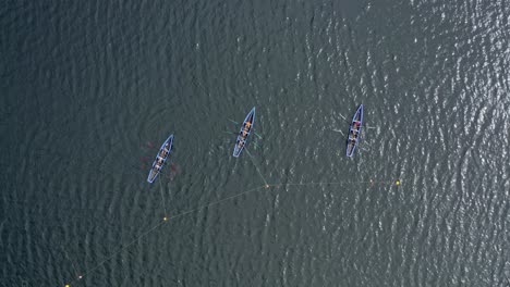 Top-down-rising-bird's-eye-view-above-currach-boats-anchored-to-buoys-at-start-line