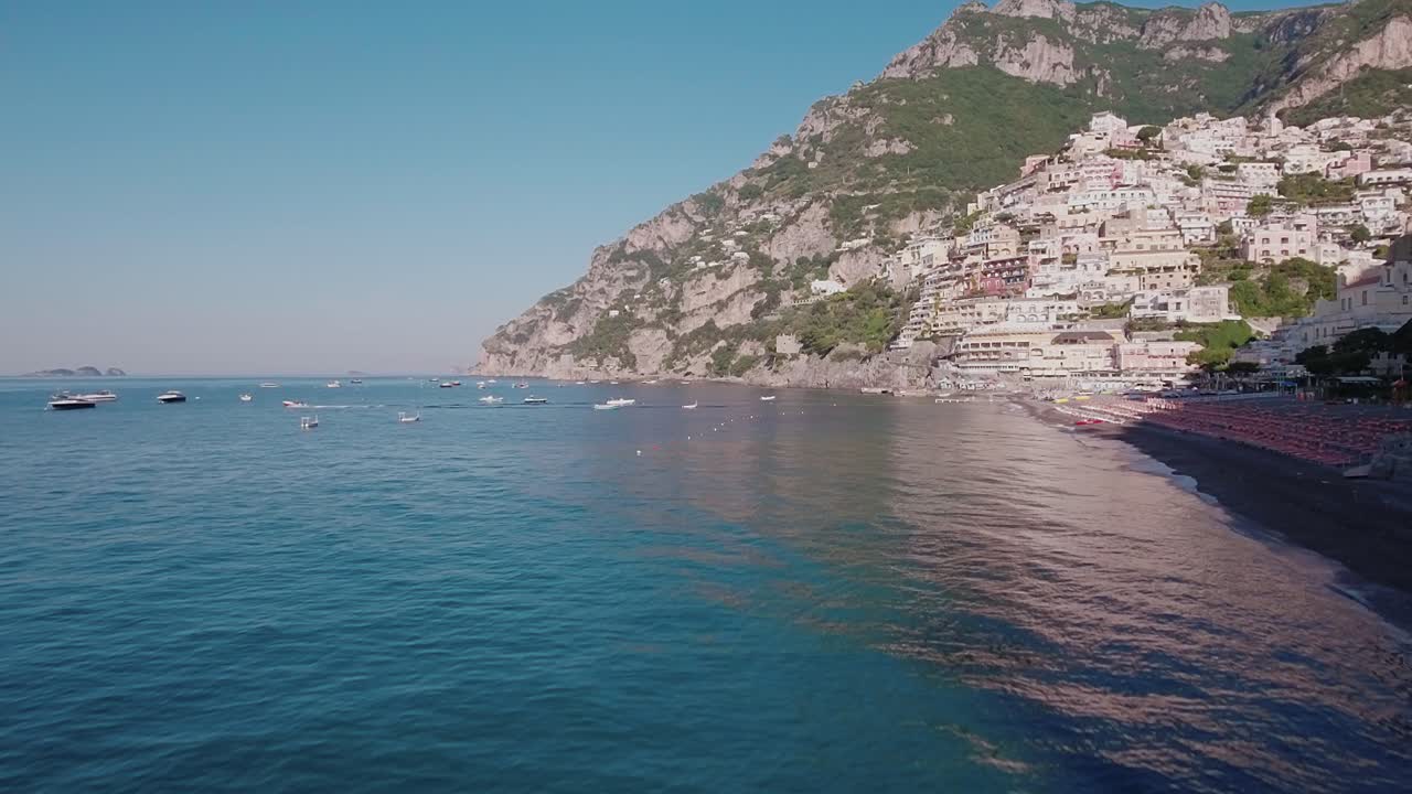 Aerial Drone shot Flying Over Ocean next to Beach in Positano, Italy at Low Altitude
