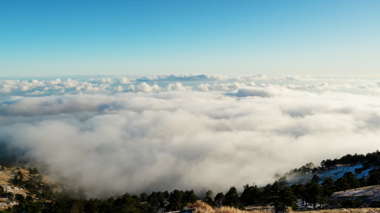 Tampilan luas dari gunung yang memperlihatkan awan yang terperangkap di lembah di bawahnya