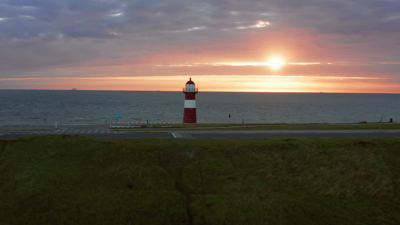 바람이 많이 부는 밝은 오렌지색 일몰 동안 웨스트카펠의 등대