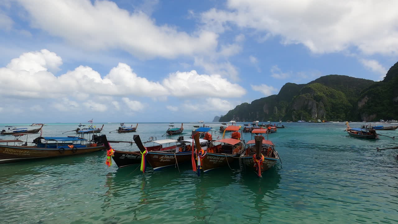 Barche tradizionali longtail sulla costa del Mare delle Andamane presso la famosa Isola di Koh Phi Phi, Thailandia, ripresa panoramica