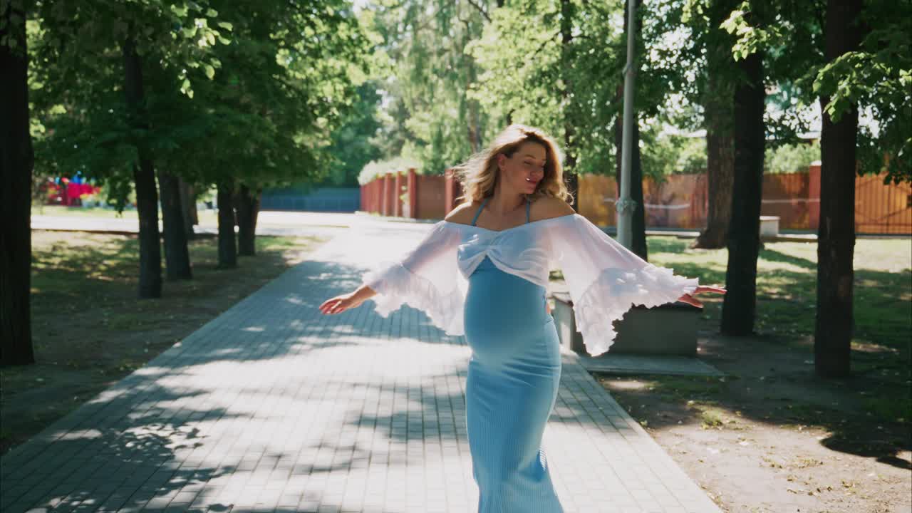 Happy Pregnant Woman Walking and Smiling in a Sunny Park