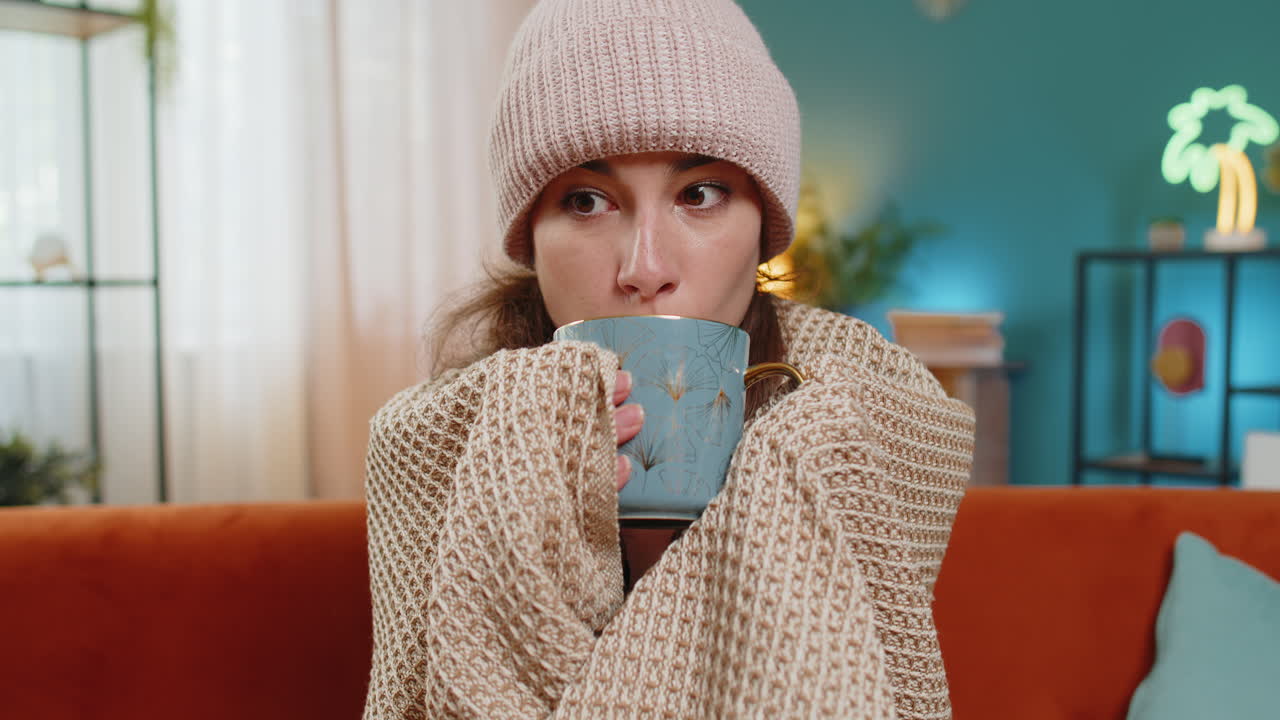 젊은 건강하지 않은 병든 아픈 여자가 따뜻한 담요로 여 커피를 마시고 집에서 감기 독감으로 얼어붙습니다.