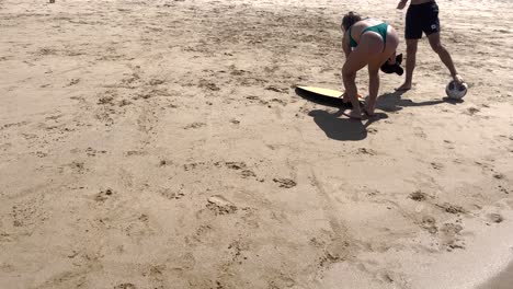 brother-and-sister-joyfully-engage-in-play-on-the-sandy-beach,-accompanied-by-a-swimming-board-and-a-beach-ball-in-caparica-beach