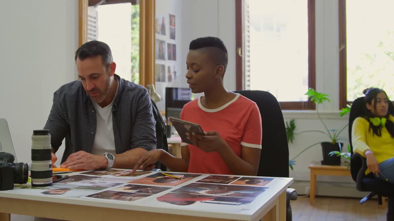 Colegas de trabalho discutindo sobre fotografias à mesa 4k