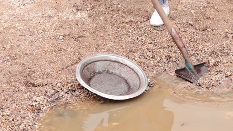 person panning for gold in muddy water