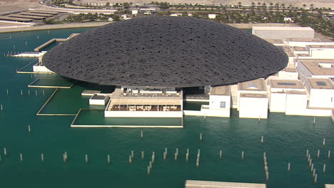 Rotating-cinematic-shot-of-the-Louvre-museum-in-Abu-Dhabi,-UAE-from-a-helicopter