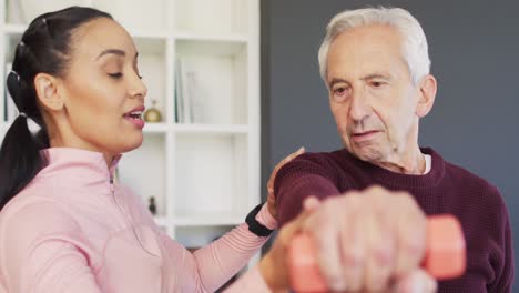 Video-of-happy-biracial-female-physiotherapist-exercising-with-caucasian-senior-man