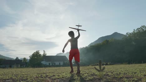 a boy plays with a toy airplane in the field